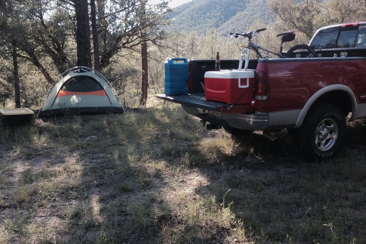 A pickup truck and tent at a dispersed campsite in a forest