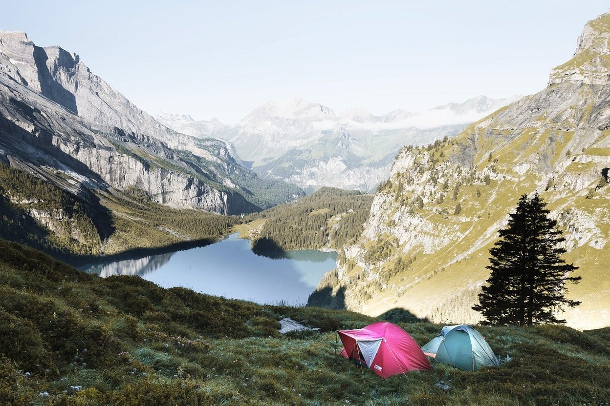 A tent at a high-elevation campsite at dawn, with frost on the grass and a sleeping bag zipped inside the door.