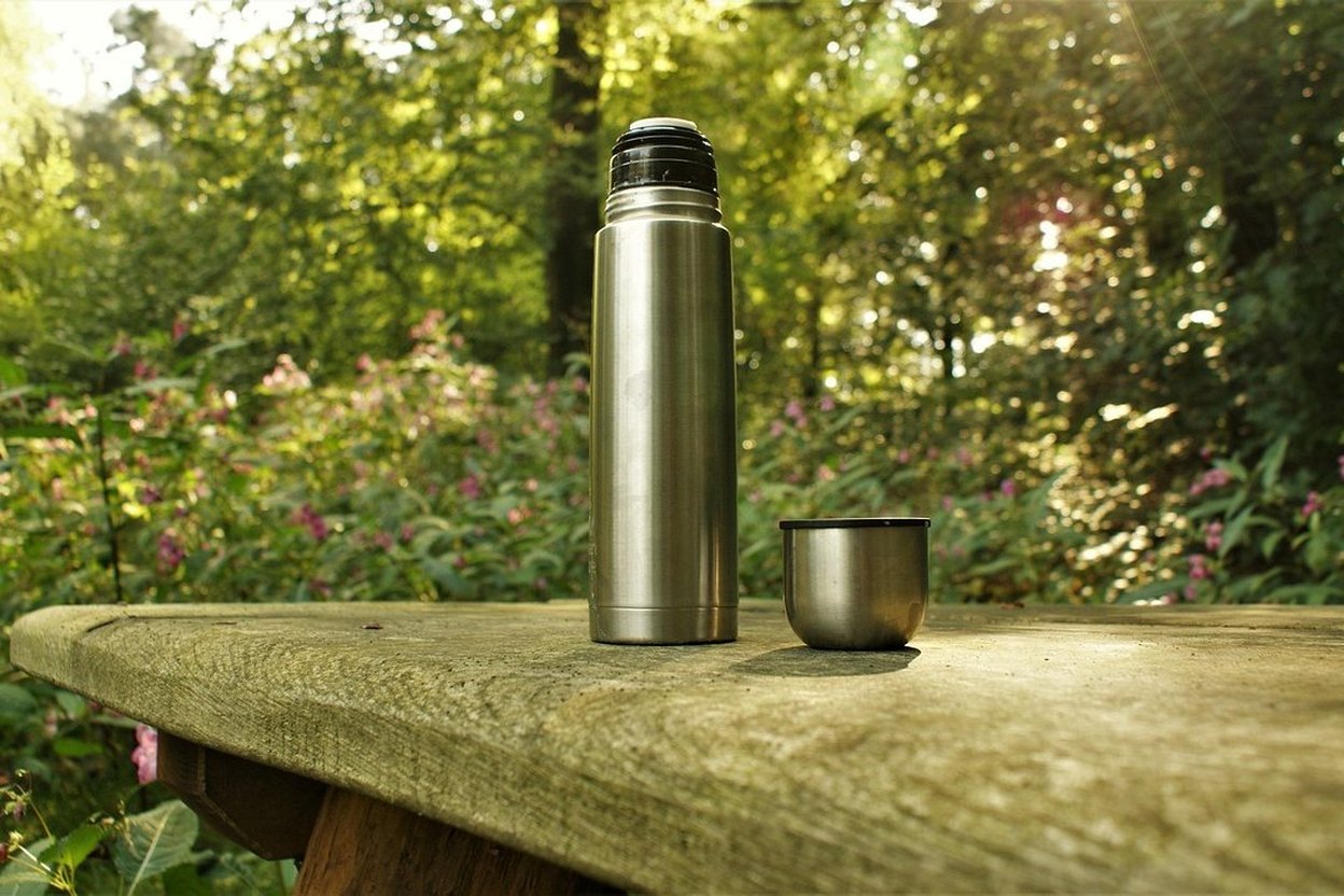 A thermos and a hot drink outdoors on a cool day