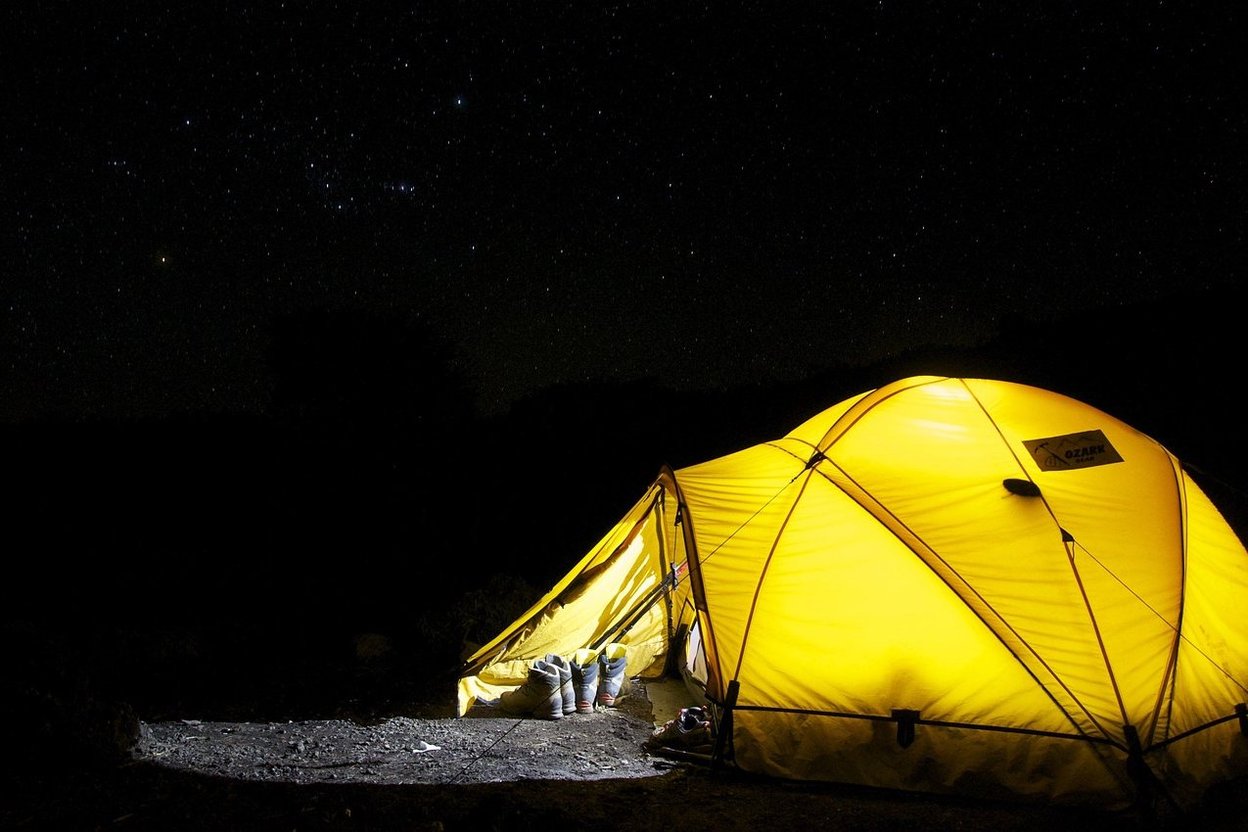A lit tent under a starry night sky